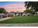 Charming single-story home with a well-manicured lawn, stone accents, and a red front door at dusk at 400 W Washington St, Minneola, FL 34715
