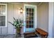 Cozy front entrance featuring a blue-framed glass door, potted plant, and a wooden bench at 500 Lake Forest Cir, Mount Dora, FL 32757