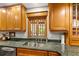 Kitchen sink with view to pool through window, green granite countertop, wooden cabinets and stainless steel appliances at 500 Lake Forest Cir, Mount Dora, FL 32757