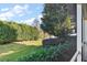 Private backyard view through a screened lanai, showcasing a lush green lawn, manicured hedges, and a glimpse of the neighborhood lake at 5046 Harbour Dr, Oxford, FL 34484