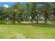 Expansive green lawn bordered by mature trees, offering scenic views of the golf course at 5090 Greens Dr, Lady Lake, FL 32159