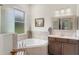 Bright bathroom features a soaking tub, wood vanity, and large window offering natural light at 5090 Greens Dr, Lady Lake, FL 32159