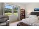 Comfortable bedroom with a large window offering serene green views, complemented by a cozy reading chair at 5090 Greens Dr, Lady Lake, FL 32159