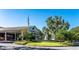 Elegant clubhouse featuring a covered entrance, manicured lawn, and mature trees at 5090 Greens Dr, Lady Lake, FL 32159