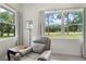 Comfortable living room space with a recliner and picturesque views of the lush, green outdoors from large windows at 5090 Greens Dr, Lady Lake, FL 32159