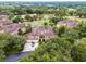 Aerial shot of the home, featuring tan roofing, driveway, and surrounded by mature trees in a lush neighborhood at 52 Camino Real Blvd, Howey In The Hills, FL 34737