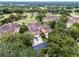 Aerial shot of a property with tan rooftops, mature trees, and proximity to a golf course and picturesque scenery at 52 Camino Real Blvd, Howey In The Hills, FL 34737