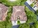 Overhead view of a tan-roofed home featuring manicured lawns, paved driveway, and verdant trees in an idyllic setting at 52 Camino Real Blvd, Howey In The Hills, FL 34737