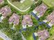 Aerial view showcasing home with a tan roof, surrounded by trees and manicured lawns in a community setting at 52 Camino Real Blvd, Howey In The Hills, FL 34737