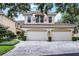 Charming two-story home with a red tile roof and a three car garage on a brick driveway at 52 Camino Real Blvd, Howey In The Hills, FL 34737