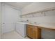 Well-lit laundry room with washer, dryer, sink, storage cabinets, and tiled floor at 52 Camino Real Blvd, Howey In The Hills, FL 34737