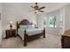 Spacious main bedroom with a large wooden bed, ceiling fan, and bright windows at 52 Camino Real Blvd, Howey In The Hills, FL 34737