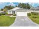 Charming single-story home with a well-manicured lawn and a patterned driveway, under a beautiful sky at 5562 Charleston Avenue, Tavares, FL 32778