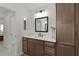 Bathroom with wood cabinets, framed mirror, and modern lighting at 6991 Sugar Creek Path, The Villages, FL 34762