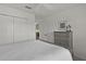 Well-lit bedroom featuring a dresser, a full-sized bed and a door to another room at 6991 Sugar Creek Path, The Villages, FL 34762