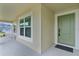 Close-up of a home's inviting front entrance, featuring a green door and a cozy porch area at 6991 Sugar Creek Path, The Villages, FL 34762