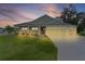 Beautiful single-story home featuring a three-car garage and a well-manicured lawn at twilight at 6991 Sugar Creek Path, The Villages, FL 34762