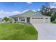 Beautiful single-story home featuring a three-car garage and a well-manicured lawn with flowerbeds at 6991 Sugar Creek Path, The Villages, FL 34762