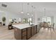 Island kitchen featuring a large island with seating, stainless appliances, and open to living spaces at 6991 Sugar Creek Path, The Villages, FL 34762