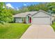 Charming single-story home with a well-manicured lawn, two-car garage and a bright red front door at 815 Forestwood Dr, Minneola, FL 34715