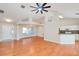 Open-concept living room with wood floors, dining area, kitchen, and a large ceiling fan at 832 Willow Run St, Minneola, FL 34715