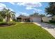 Charming single-story home with a well-manicured lawn, a palm tree, and an attached garage at 8537 Se 177Th Bartram Loop, The Villages, FL 32162