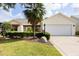 Inviting single-story home with manicured landscaping, a two-car garage, and a charming front yard at 891 Lucky Ln, The Villages, FL 32162