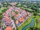An aerial view showcasing a neighborhood with tile roofs beside a manicured golf course and winding waterways at 903 Santa Anna Ln, Lady Lake, FL 32159