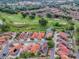 An aerial shot featuring homes with red tile roofs adjacent to a golf course with sand traps and water hazards at 903 Santa Anna Ln, Lady Lake, FL 32159