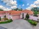 Inviting single-story home showcasing a beautiful terra cotta roof, lush landscaping, and a spacious driveway at 903 Santa Anna Ln, Lady Lake, FL 32159