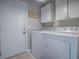Clean and bright laundry room featuring a white washer and dryer, ample cabinet space, and convenient access door at 903 Santa Anna Ln, Lady Lake, FL 32159
