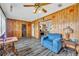 Comfortable living room featuring knotty pine walls and laminate flooring with a ceiling fan and adjacent kitchen at 1 W Pierce Ave, Orlando, FL 32809
