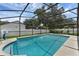 Inviting screened-in pool area with a clear blue pool, white fence, and surrounding greenery at 1109 Needlewood Loop, Oviedo, FL 32765