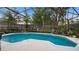 Backyard view featuring pool with screened enclosure, lush landscaping, and garden area at 1130 Woodsong Way, Clermont, FL 34714