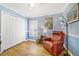 A bright bedroom with hardwood floors, a red chair, and natural light, with closet storage at 15169 Harrowgate Way, Winter Garden, FL 34787