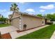 Beige single-Gathering home showing the garage and a well-kept sidewalk and lawn at 15169 Harrowgate Way, Winter Garden, FL 34787