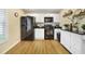 A kitchen area with black appliances, white cabinets, and wood flooring at 15169 Harrowgate Way, Winter Garden, FL 34787