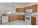 Well-equipped kitchen with wood cabinets, white appliances, granite countertops, and tile flooring at 1730 Dorset Dr, Mount Dora, FL 32757