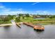 Aerial view of boat ramp leading to lake with dock and community tennis courts in the distance at 17428 Woodfair Dr, Clermont, FL 34711