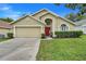 Charming single-story home featuring a well-maintained lawn, a two-car garage, and a welcoming red front door at 17428 Woodfair Dr, Clermont, FL 34711