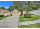 Inviting single-story home with mature landscaping, a spacious driveway, and a vibrant red front door at 17428 Woodfair Dr, Clermont, FL 34711