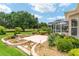 Beautifully landscaped backyard featuring lush greenery, mature trees, a water fountain, and a screened lanai at 219 Carrera Dr, The Villages, FL 32159