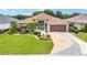 Charming single-story home with a well-manicured lawn, landscaped garden beds, and a striking turquoise front door at 219 Carrera Dr, The Villages, FL 32159