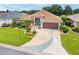 Beautiful single-story home featuring manicured landscaping, a decorative driveway, and a charming turquoise front door at 219 Carrera Dr, The Villages, FL 32159