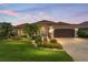 Charming single-story home with lush landscaping, a brown two-car garage, and a bright blue front door at 219 Carrera Dr, The Villages, FL 32159