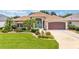 Inviting single-story residence featuring lush landscaping, vibrant flowerbeds, and an eye-catching turquoise front door at 219 Carrera Dr, The Villages, FL 32159
