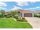 Charming single-story home with lush landscaping, a brown two-car garage, and a bright blue front door at 219 Carrera Dr, The Villages, FL 32159