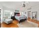 Bright main bedroom featuring wood floors, ceiling fan, and a sitting area near the window at 219 Carrera Dr, The Villages, FL 32159