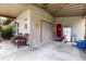 Covered carport with wicker furniture, storage, and a red front door at 2202 Butler St, Leesburg, FL 34748