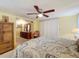Stylish main bedroom with a ceiling fan, dresser, and seating area, a comfortable place to unwind at 239 Rue De Fontaine, Tavares, FL 32778